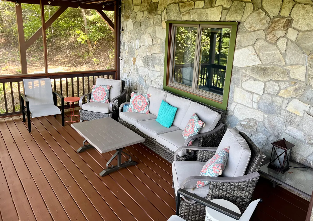 This exterior image features a comfortable seating area with plush decorative pillows set against a stone wall. The cozy arrangement encourages relaxation, reading, or unwinding outdoors while still enjoying the fresh mountain air and peaceful environment.
