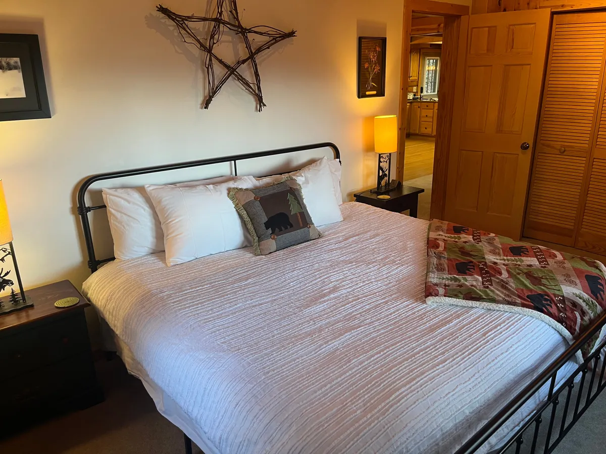 An inviting bedroom with a soft bed, decorative pillows, a star accent on the wall, and lamps providing warm, ambient light. The mood is restful and intimate, perfect for winding down after a day of adventure.